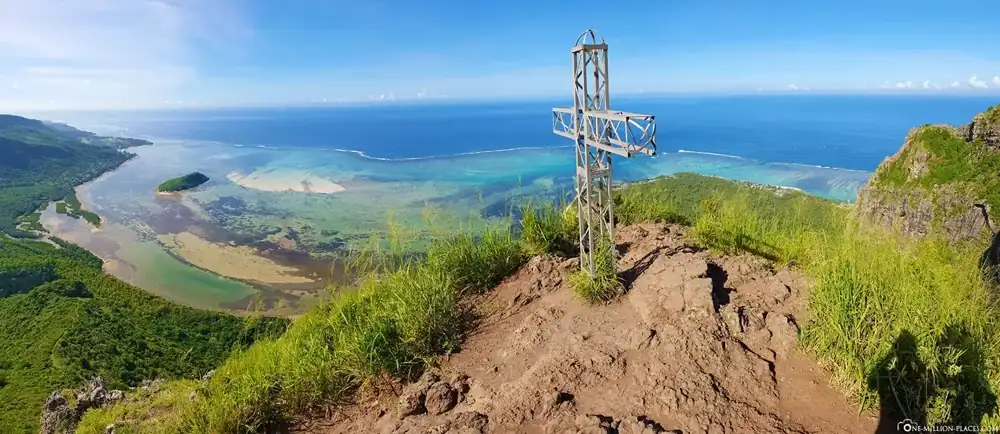 Mountain viewpoint overlooking fields, coast, and distant hills
